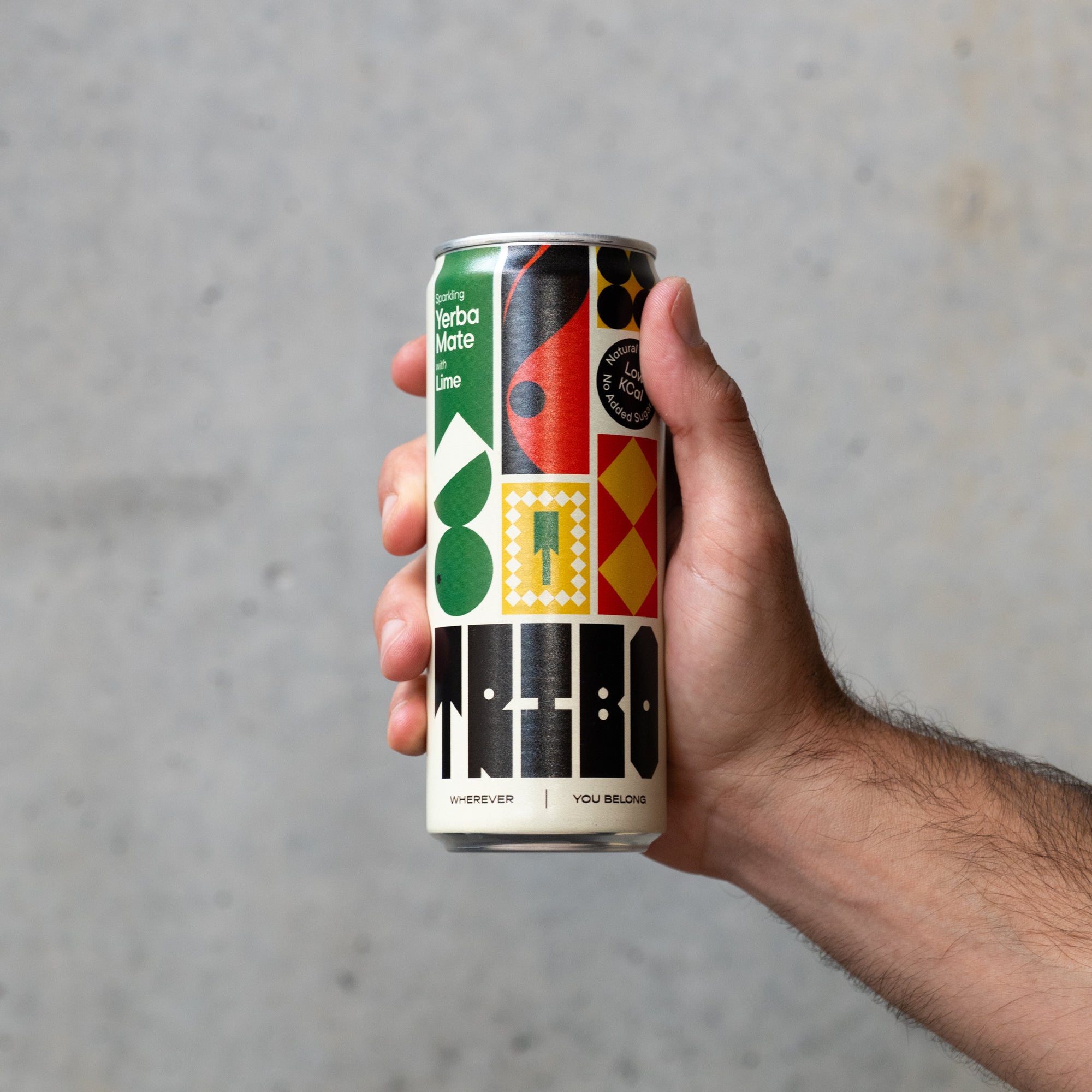 Hand holding a colorful can against a gray concrete background